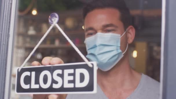 Male Owner Small Business Wearing Face Mask Turning Open Sign — Stockvideo