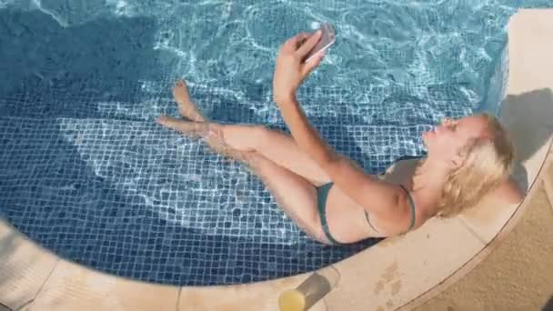 穿比基尼的女人在户外游泳池里用手机自拍然后把手机扔到水里 — 图库视频影像