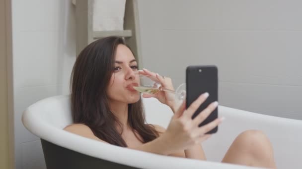 Женщина Лежит Отдыхает Ванной Дома Позирует Селфи Мобильном Телефоне Пьет — стоковое видео