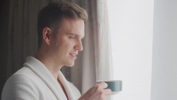 穿着浴衣的男人在宾馆或温泉站在敞开的窗帘旁 — 图库视频影像