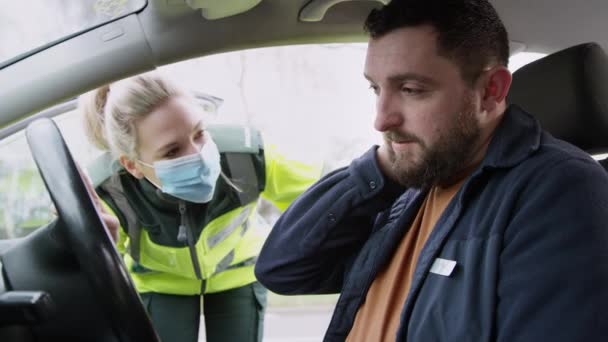 道路交通事故に巻き込まれたむち打ち首の負傷を持つ男性ドライバーを助ける女性救急車 — ストック動画