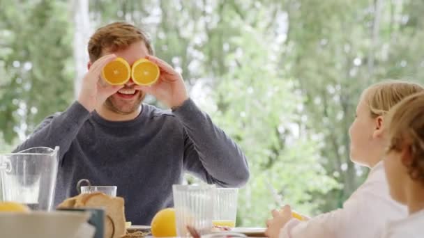 Father Making Children Laugh Breakfast Table Making Face Cut Oranges — Stockvideo