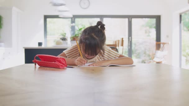 在关禁闭期间 年轻的亚洲女孩在家上学在厨房的饭桌边工作写书 — 图库视频影像