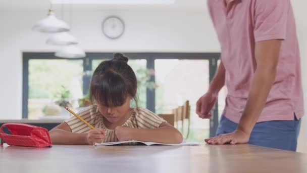 亚洲父亲帮助在家上学女儿在餐桌边工作在厨房写书 — 图库视频影像