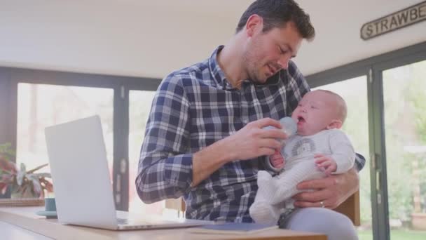 직장에 다니는 다재다능 아버지가 동작으로 아기에게 먹이면서 전화로 이야기하는 — 비디오