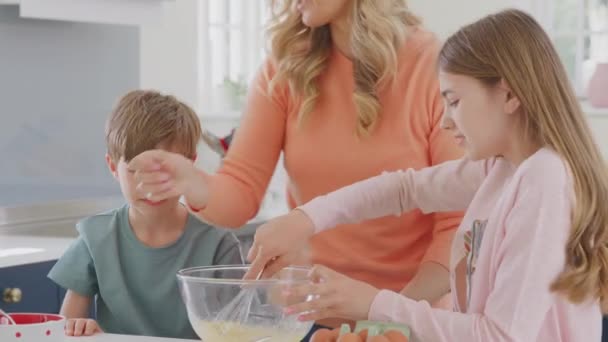 一緒に楽しいベーキングケーキを持っている家庭で台所で2人の子供を持つ母親 — ストック動画