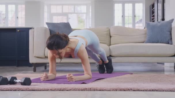 穿着健身服装的女人在家里休息时做伸展运动 用手举重 慢动作射击 — 图库视频影像