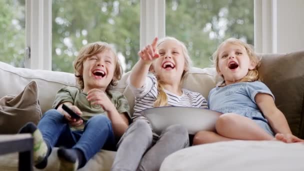 Trójka Dzieci Siedząca Kanapie Domu Śmiejąca Się Oglądająca Telewizję Popcornem — Wideo stockowe