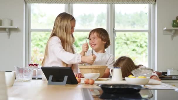 穿着睡衣在厨房做松饼的孩子们在家中跟随数码桌面上的食谱 — 图库视频影像