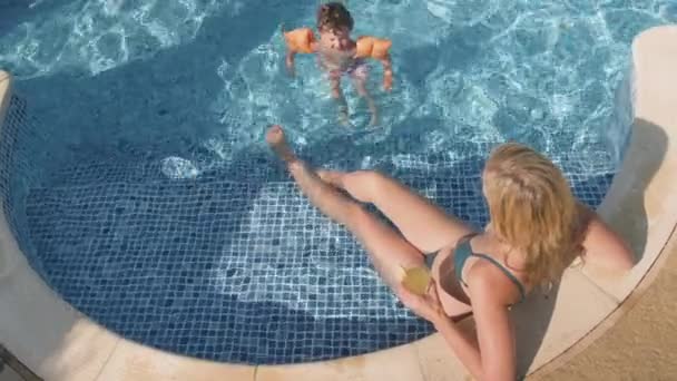 Matka Relaxuje Venkovním Bazénu Studeným Pitím Jako Syn Náramky Hraje — Stock video