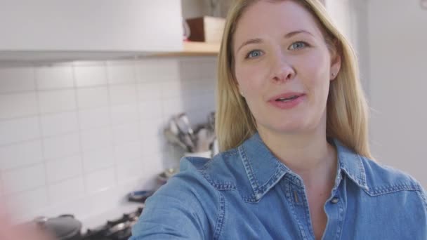 彼女は自宅でキッチンでカメラを運ぶとして女性のブログの撮影の視点 スローモーションで撮影 — ストック動画