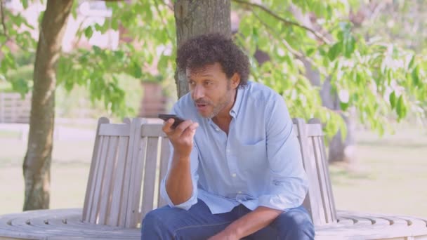 Volwassen Man Zitten Park Bank Onder Boom Zomer Praten Mobiele — Stockvideo