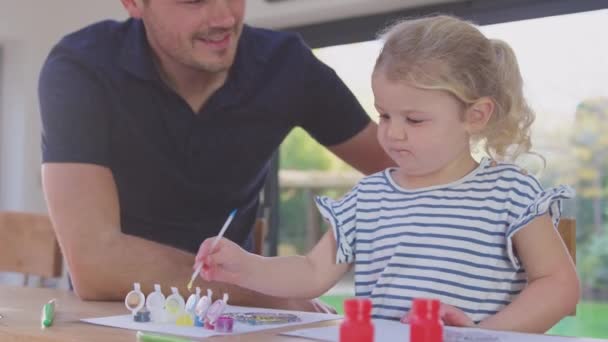 父亲和年幼的女儿在家里玩的很开心 一起坐在桌旁 一起粉刷装饰 动作缓慢 — 图库视频影像