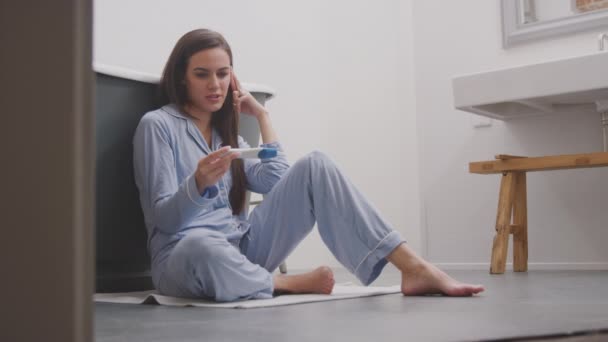 Aufgeregte Frau Sitzt Mit Positivem Schwangerschaftstest Auf Badezimmerboden — Stockvideo