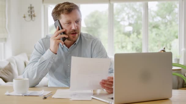 Homem Chamada Telefone Casa Com Computador Portátil Revisando Finanças Domésticas — Vídeo de Stock