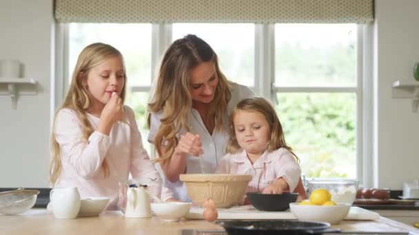 母と二人の娘は一緒に自宅で台所でパジャマ焼きを着ています — ストック動画
