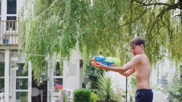 夏の庭で水の戦いのための水のピストルを使用して楽しい水泳の衣装を身に着けている男の子 スローモーションで撮影 — ストック動画