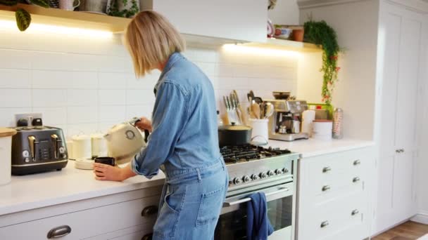 成熟した女性で家でキッチン作るコーヒー前にデジタルタブレットを見て 遅い動きで撮影 — ストック動画