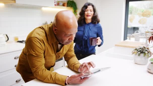 Mature Couple Home Kitchen Drinking Coffee Looking Digital Tablet Together — Stockvideo