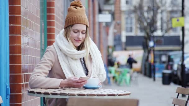 Yoğun Şehir Anayolundaki Kahve Dükkanının Önünde Oturan Kadın Cep Telefonuyla — Stok video