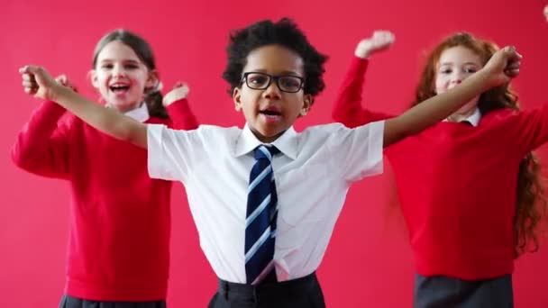 스튜디오 배경을 배경으로 카메라 통쾌하게 환호하는 제복을 초등학생들 동작으로 — 비디오