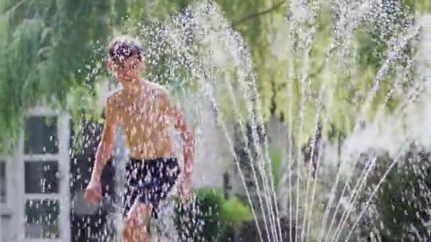 Chłopiec Dziewczyna Stroju Kąpielowym Skacząc Przez Wodę Zraszacza Ogrodowego Letnim — Wideo stockowe