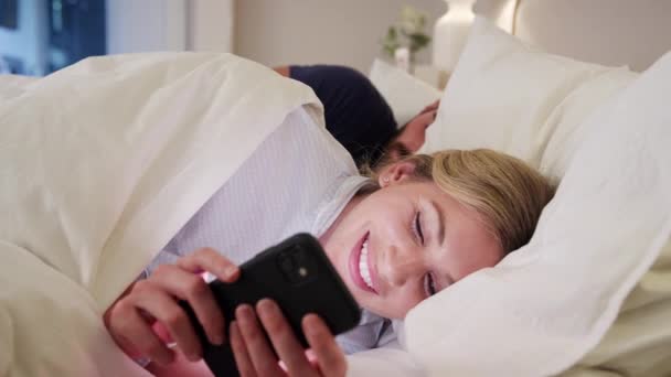 与晚上躺在床上的女人在手机上发送秘密短信的情侣 慢动作拍摄 — 图库视频影像