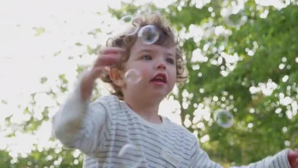 在花园追逐和爆破气泡中快乐的小男孩 慢镜头拍摄 — 图库视频影像