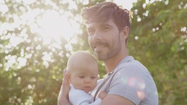 彼は公園や庭で彼女の屋外を保持しているとして愛する父抱っことキス赤ちゃんの娘 スローモーションで撮影 — ストック動画