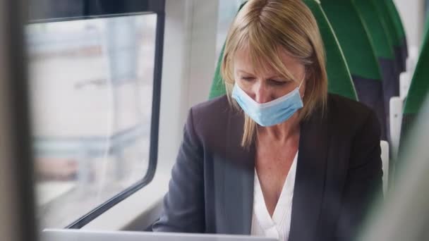 Reife Geschäftsfrau Mit Gesichtsmaske Zug Bei Der Arbeit Laptop Aufgenommen — Stockvideo