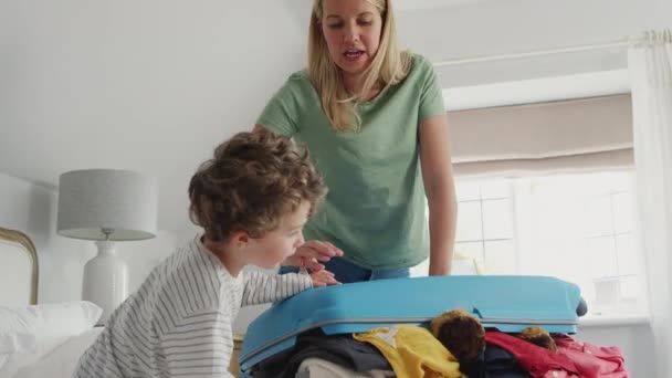 息子ヘルプ母親にパックするために家族の休暇のためにスーツケースに立つことによってそれをシャットダウンする スローモーションで撮影 — ストック動画