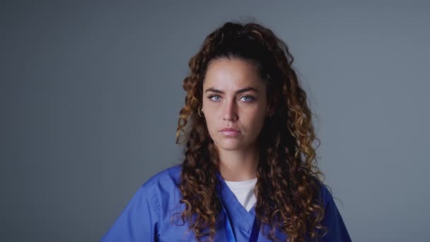スタジオ肖像画の若い女性看護師身に着けているスクラブに対して灰色の背景 スローモーションで撮影 — ストック動画