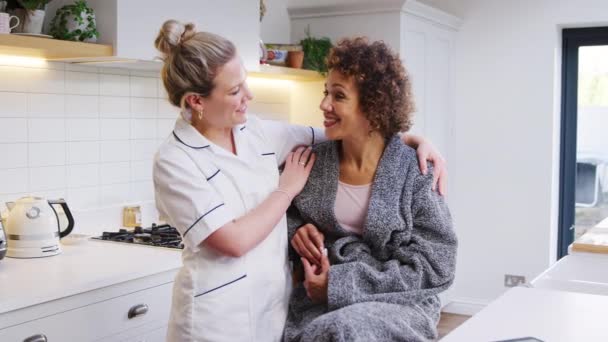 Mature Woman Dressing Gown Talking Female Nurse Kitchen Home Shot — Stock Video