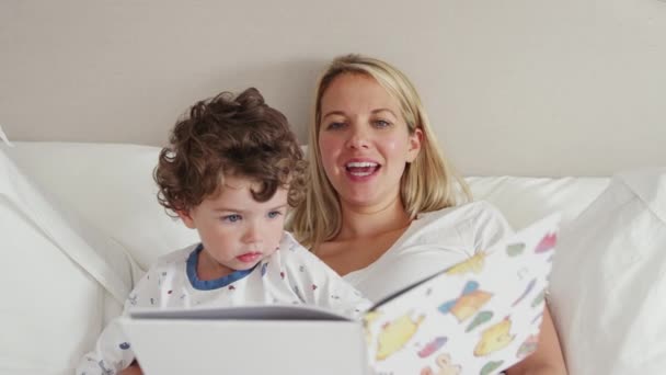 妈妈在睡觉前给穿睡衣的儿子读睡前故事 动作缓慢 — 图库视频影像