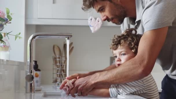 Padre Ayudando Hijo Pequeño Lavarse Las Manos Fregadero Cocina Durante — Vídeos de Stock