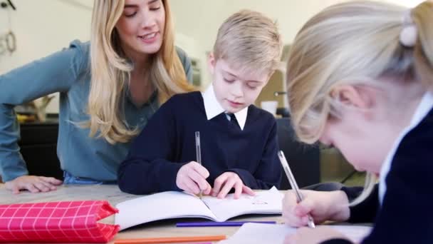 Lächelnde Mutter Hilft Sohn Und Tochter Schuluniform Bei Den Hausaufgaben — Stockvideo
