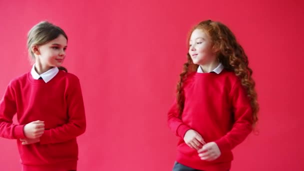 两名小学女生背靠背站在红色工作室背景下的肖像 慢镜头拍摄 — 图库视频影像