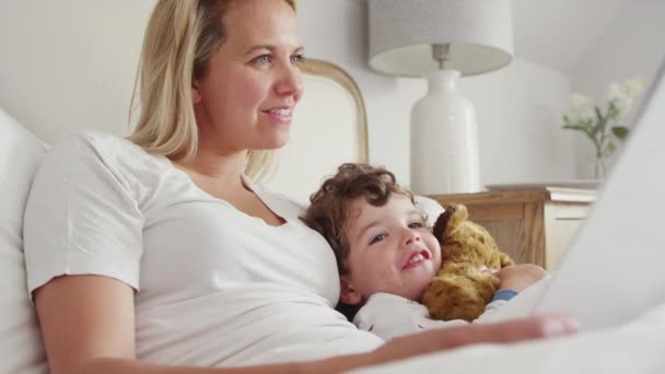 母読書就寝時の話へ息子を身に着けているパジャマ抱っこテディベア前に寝る スローモーションで撮影 — ストック動画