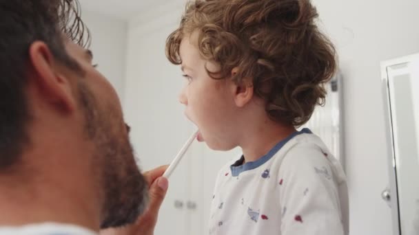 Закрытие Отца Помогающего Маленькому Сыну Чистить Зубы Ванной Снято Замедленной — стоковое видео