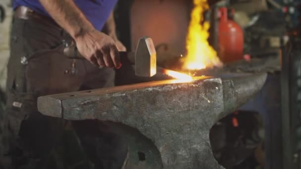 火花と背景に燃えるフォージを持つアンビル上の男性鍛冶屋の金属細工をハンマーの閉じる スローモーションで撮影 — ストック動画