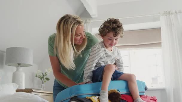 Figlio Aiutare Madre Fare Bagagli Vacanze Famiglia Sedendosi Sulla Valigia — Video Stock