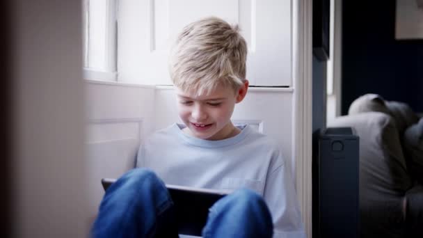 Evde Pencere Kenarına Oturmuş Dijital Tabletle Oynayan Genç Bir Çocuk — Stok video