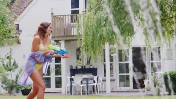 여름철에 정원에서 물총으로 싸우는 수영복을 어머니 와아들 동작으로 — 비디오