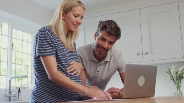 自宅で妊娠中の妻とのカップル 製品やサービスをオンラインでラップトップを使用して購入 スローモーションで撮影 — ストック動画