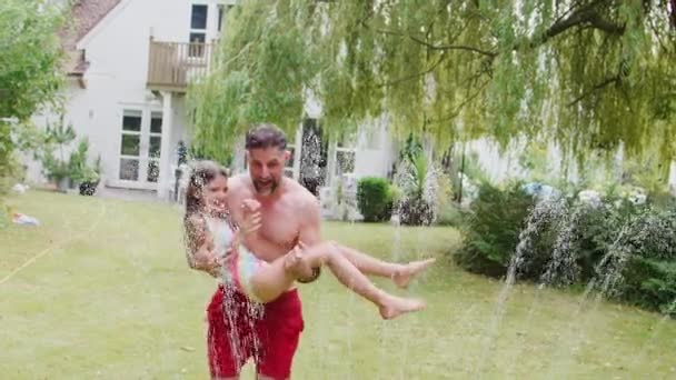 Vader Draagt Dochter Door Het Water Van Tuin Sprinkler Plezier — Stockvideo