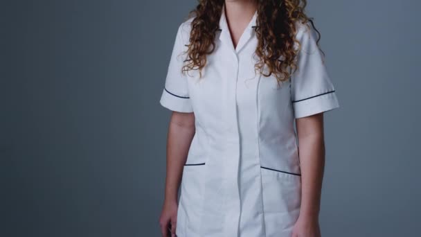 スタジオポートレートの若いです女性看護師の制服を着て背景グレー 遅い動きで撮影 — ストック動画
