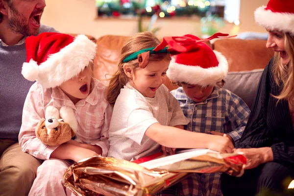 Familie Mit Weihnachtsmützen Sitzt Hause Auf Sofa Und Öffnet Weihnachtsgeschenke — Stockfoto