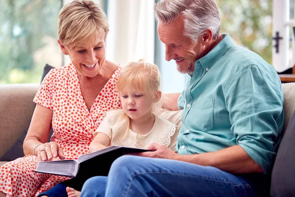 Abuelos Sentados Sofá Con Nieta Casa Lectura Libro Juntos — Foto de Stock