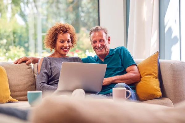 Rentnerehepaar Auf Sofa Hause Einkaufen Oder Urlaub Laptop Buchen — Stockfoto