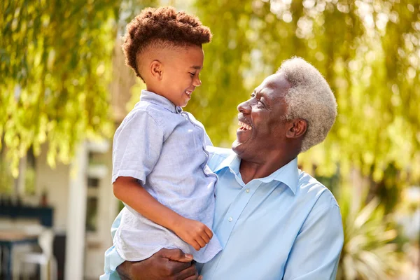 Amando Abuelo Sosteniendo Nieto Brazos Jardín Casa —  Fotos de Stock